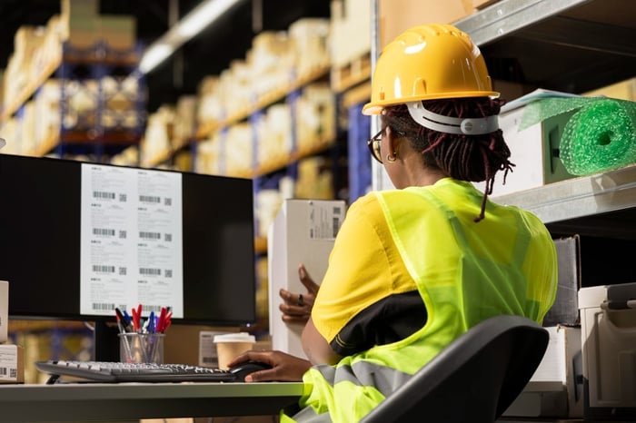 Trabajadora con casco revisa etiquetas de códigos de barras en sistema de Warehouse Management
