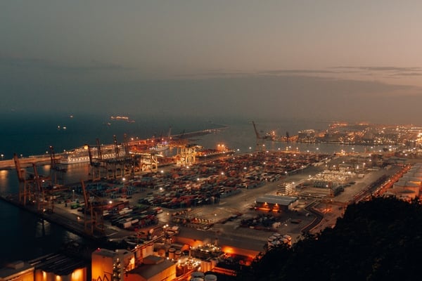 Vista aérea nocturna de terminal portuaria con contenedores y grúas, nodo logístico para operaciones de nearshoring en México