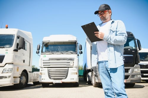 Coordinador logístico revisando inventario de flotilla y dimensiones de cajas de tráiler