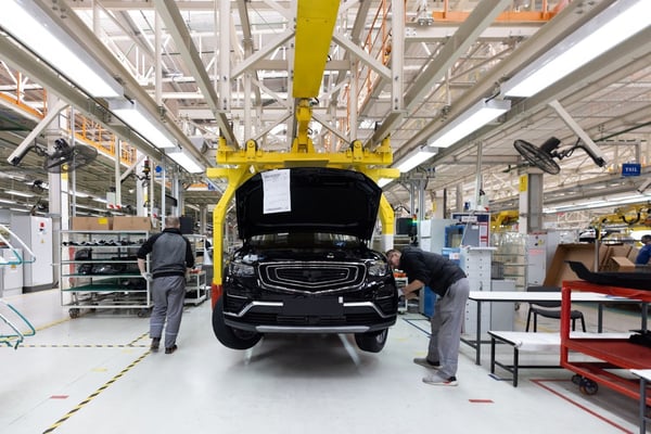 Línea de producción automotriz con técnicos trabajando en el ensamblaje de vehículos en una planta moderna